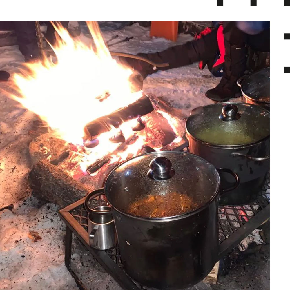 Hier ist das Lagerfeuer zu sehen, auf dem sich die Teilnehmer der Charity-Schneewanderung ihr Essen zubereiten.