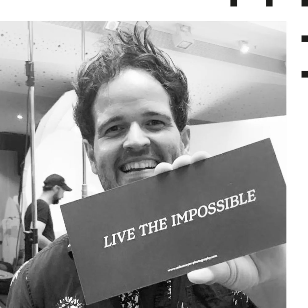 Starfotograf Mike Meyer hält eine Karte mit der Aufschrift "Live the Impossible" in die Kamera
