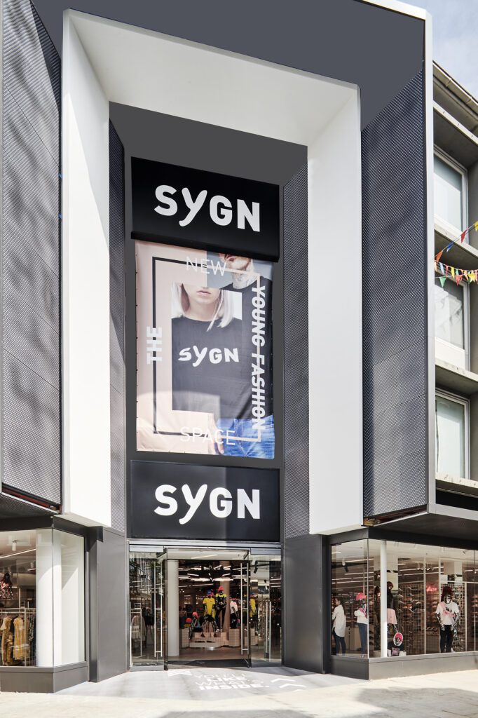 Eingang zur SYGN Filiale in Osnabrück – moderner Store für Young Fashion mit großem Werbebanner und Glasfassade